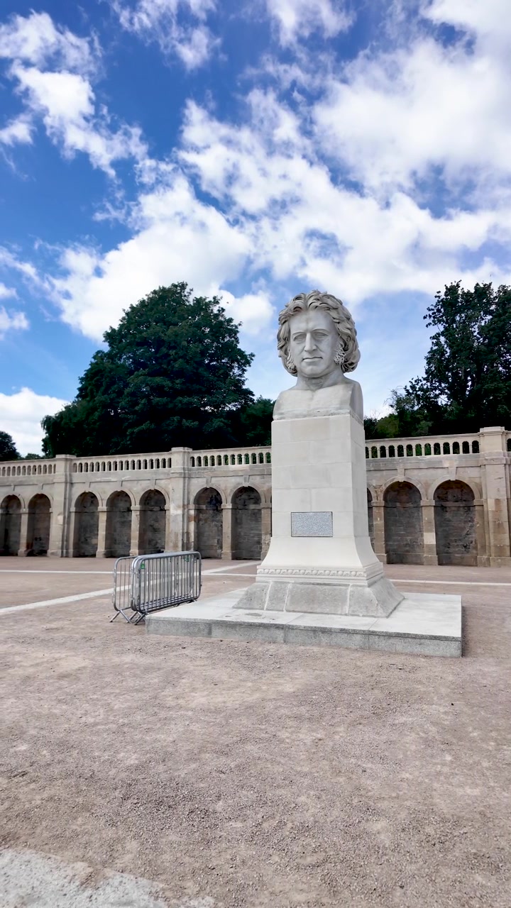 Enorme busto di Sir Joseph Paxton su un'ampia piazza davanti alla terrazza ad arco del Crystal Palace Park sotto un cielo blu con nuvole. Video verticale