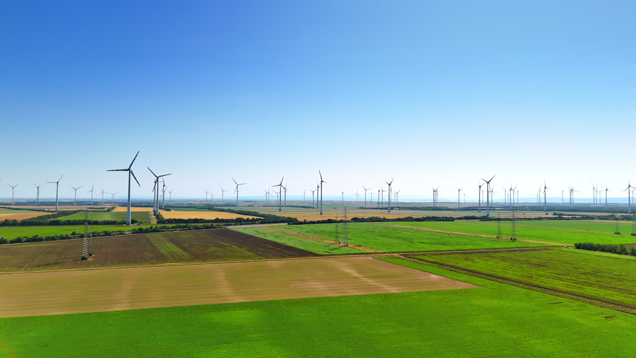 Flight over the picturesque countryside with wind farms. Green energy being produced by wind turbines