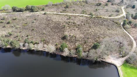 Aerial-backwards-shot-showing-heathland-and-Squabmoor-Reservoir-Woodbury-Devon-England-on-a-beautiful-summers-day