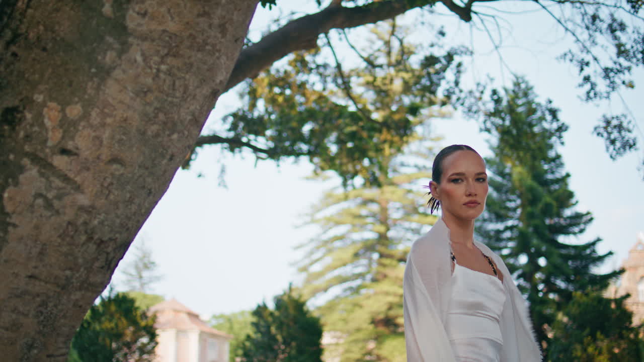 신경 쓰지 않는 여자가 정원을 포즈를 취하고 카메라를 가게 쳐다보고 있습니다. 아름다운 소녀가 눈을 감고 있습니다.