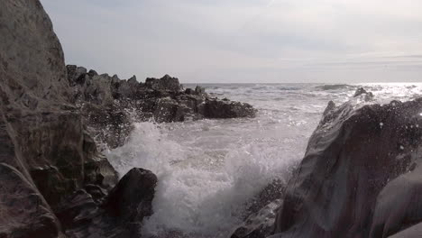 waves breaking in narrow gap on a rocky beach at sunset