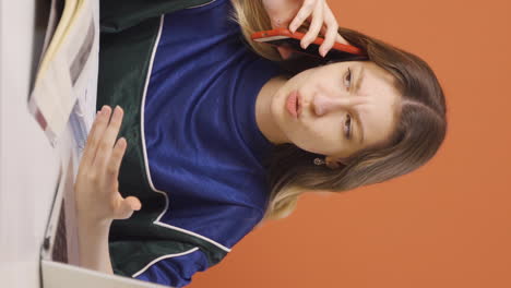 Vertical-video-of-Young-woman-using-laptop-nervously-talking-on-the-phone.