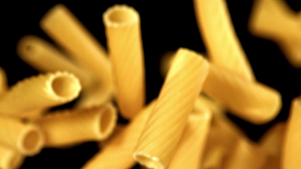 Rigatoni secchi che cadono in super slow motion su sfondo nero