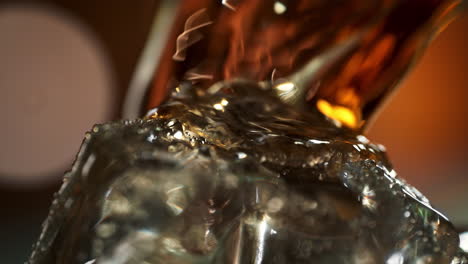 whisky pouring over ice cube and splashing in slow motion, whisky on the rocks