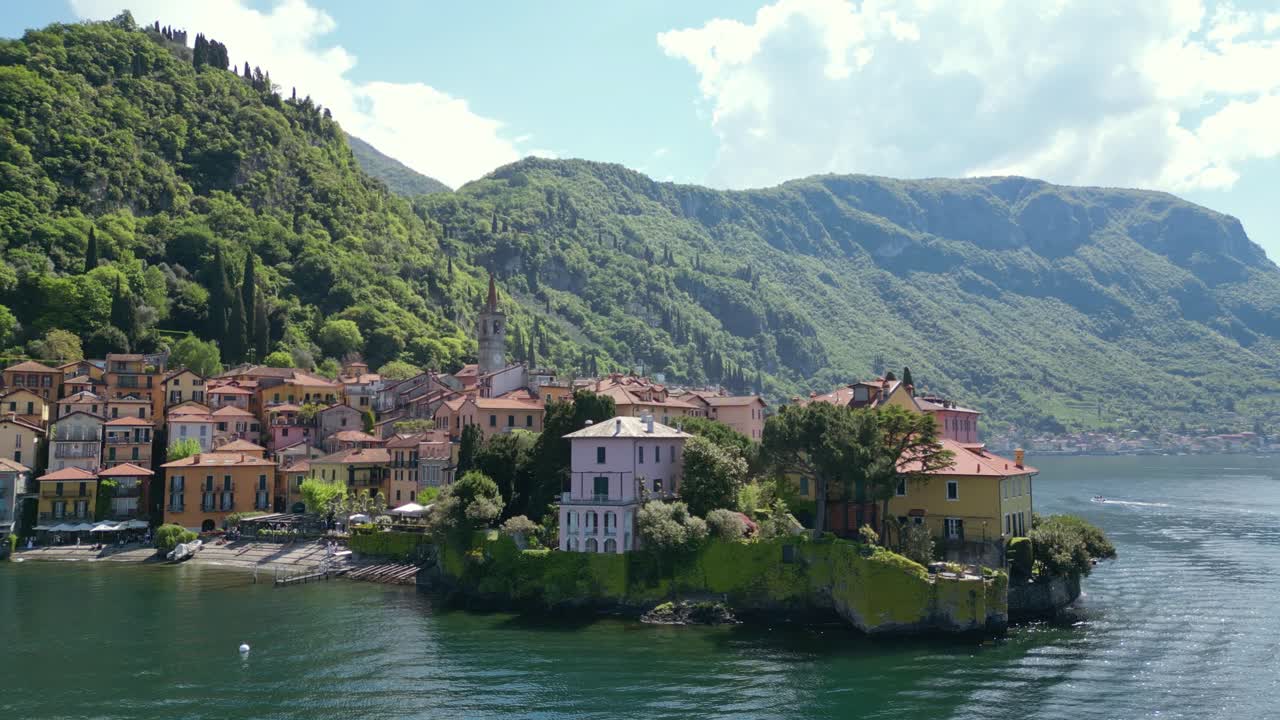 Fly over Varenna on Lake Como, capturing its iconic lakeside church, colorful houses, and the stunning mountain backdrop