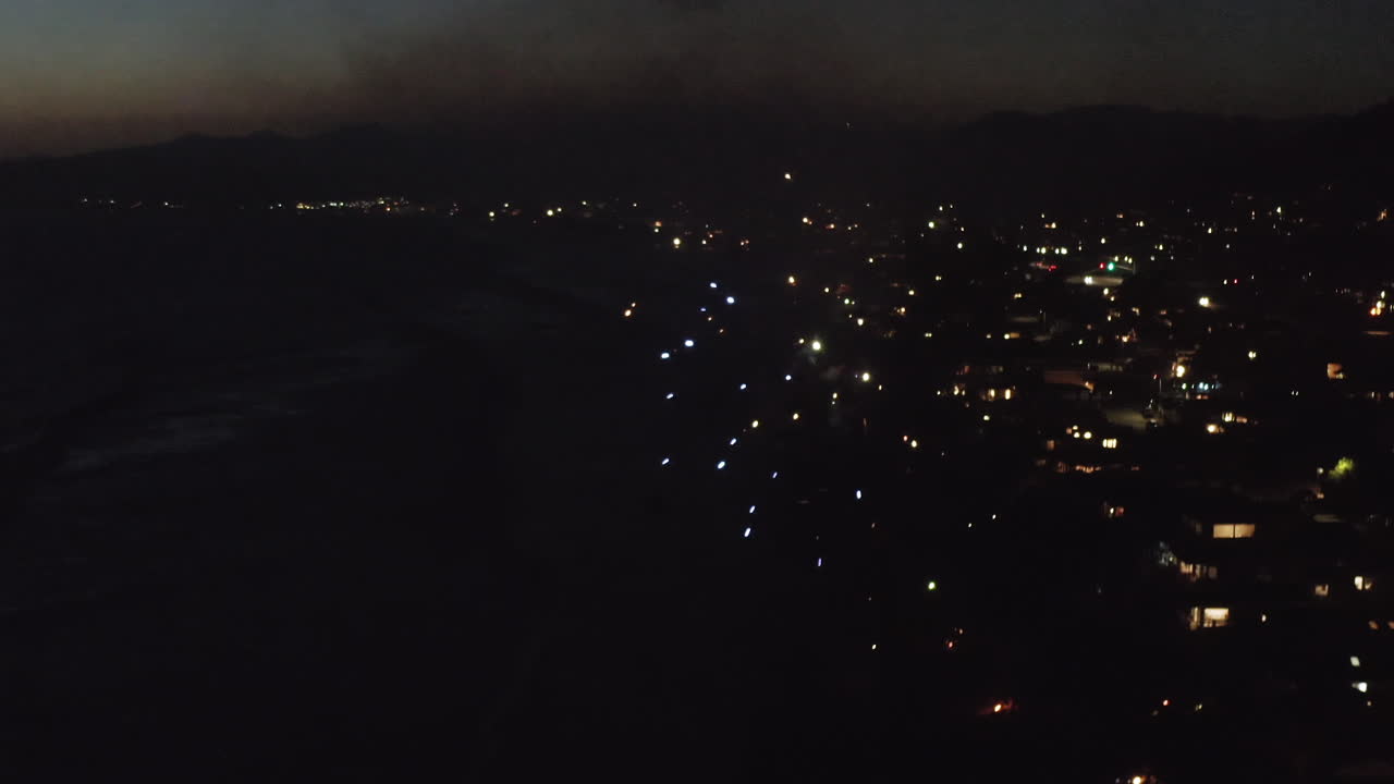 Nighttime Aerial View of Coastal City with Fireworks Display