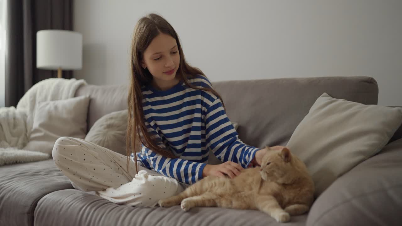 Girl petting her cat on the couch
