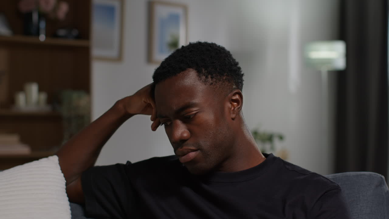 Unhappy And Depressed Young Man Sitting On Sofa At Home Looking Anxious And Worried Resting Head On Hand 6