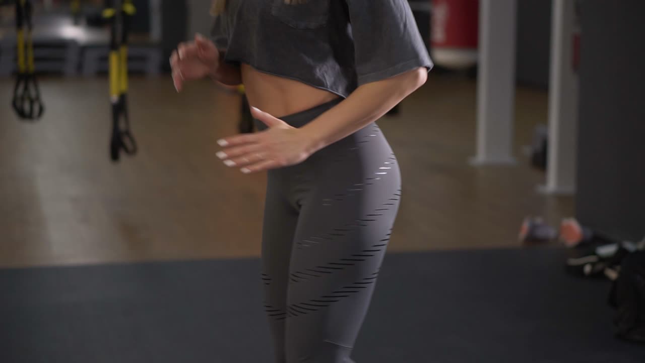 Step platforms. Girl in sports grey leggings and top doing exercises for aerobics. The concept of tightening in the gym for weight loss. Aimed footage of woman's torso