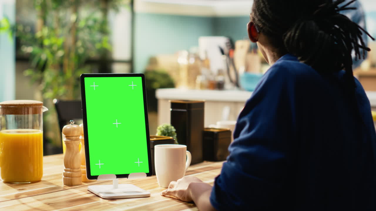 Woman using tablet with green screen at breakfast