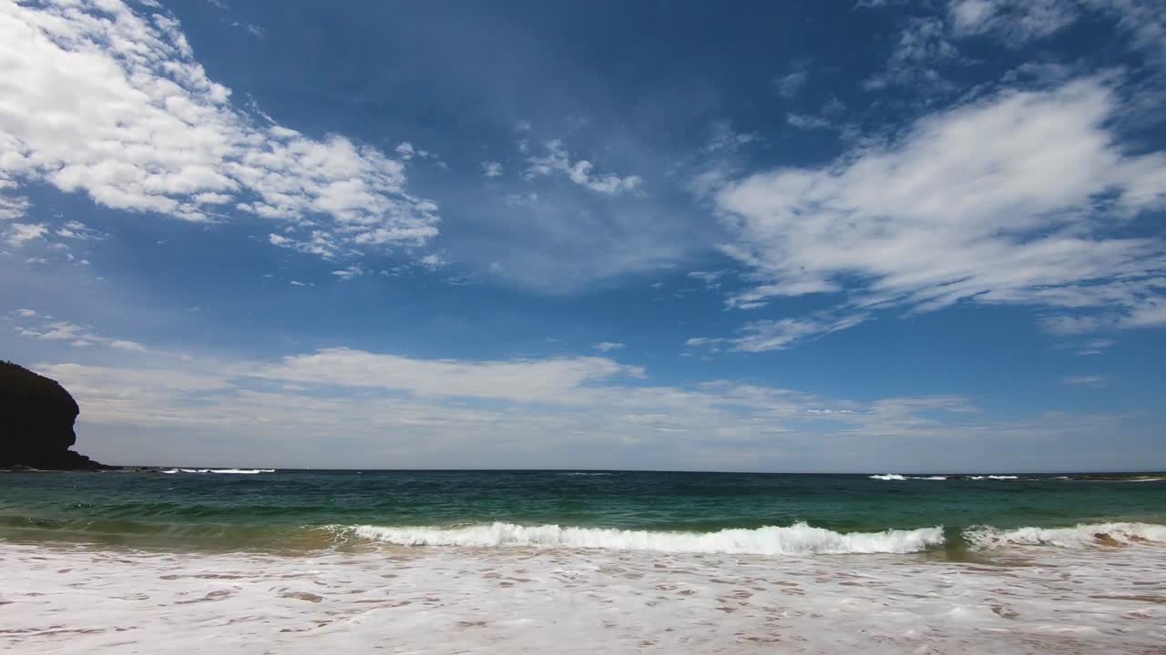 Time-lapse di onde che si infrangono sulla spiaggia con nuvole che si muovono velocemente allontanandosi dalla riva
