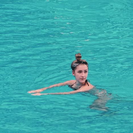 una joven sensual relajándose en la piscina.