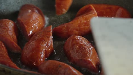 slices of dried sausage sizzle in a hot pan, releasing savory aromas