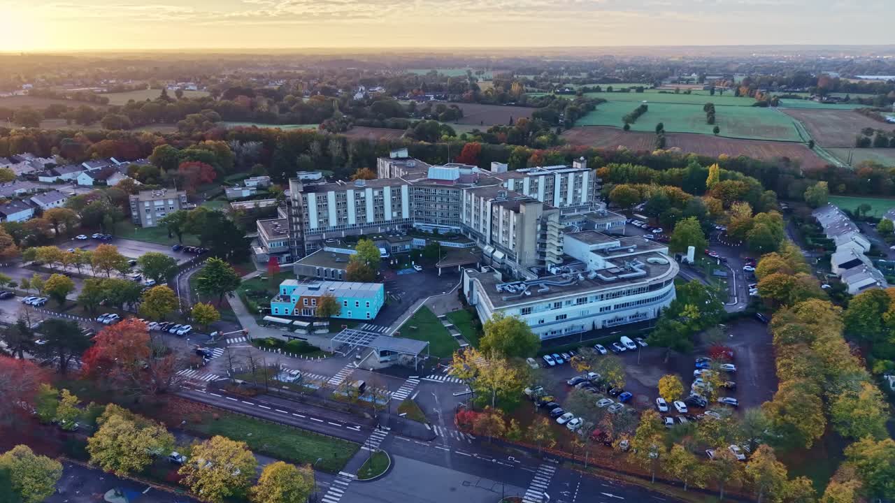Morning light reveals large hospital complex with surrounding buildings and soft haze over the city, CHU Rennes. Aerial drone establish