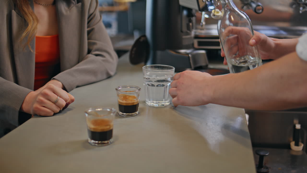 Waiter hand pouring water at bar counter closeup. Businesswoman talking break
