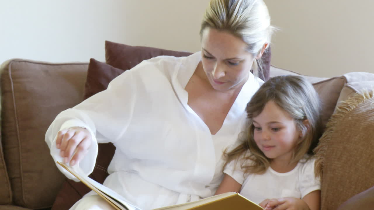 Entspannte Mutter liest mit Tochter ein Buch.