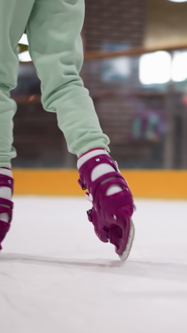 primer plano de alguien patinando en una pista de hielo con patines púrpuras y pantalones de color ceniza, con vista de luz borrosa
