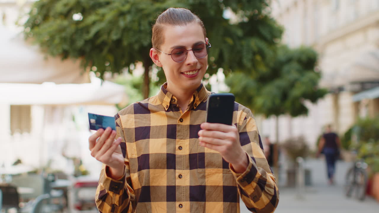 Man using credit bank card smartphone while transferring money purchases online shopping outdoors