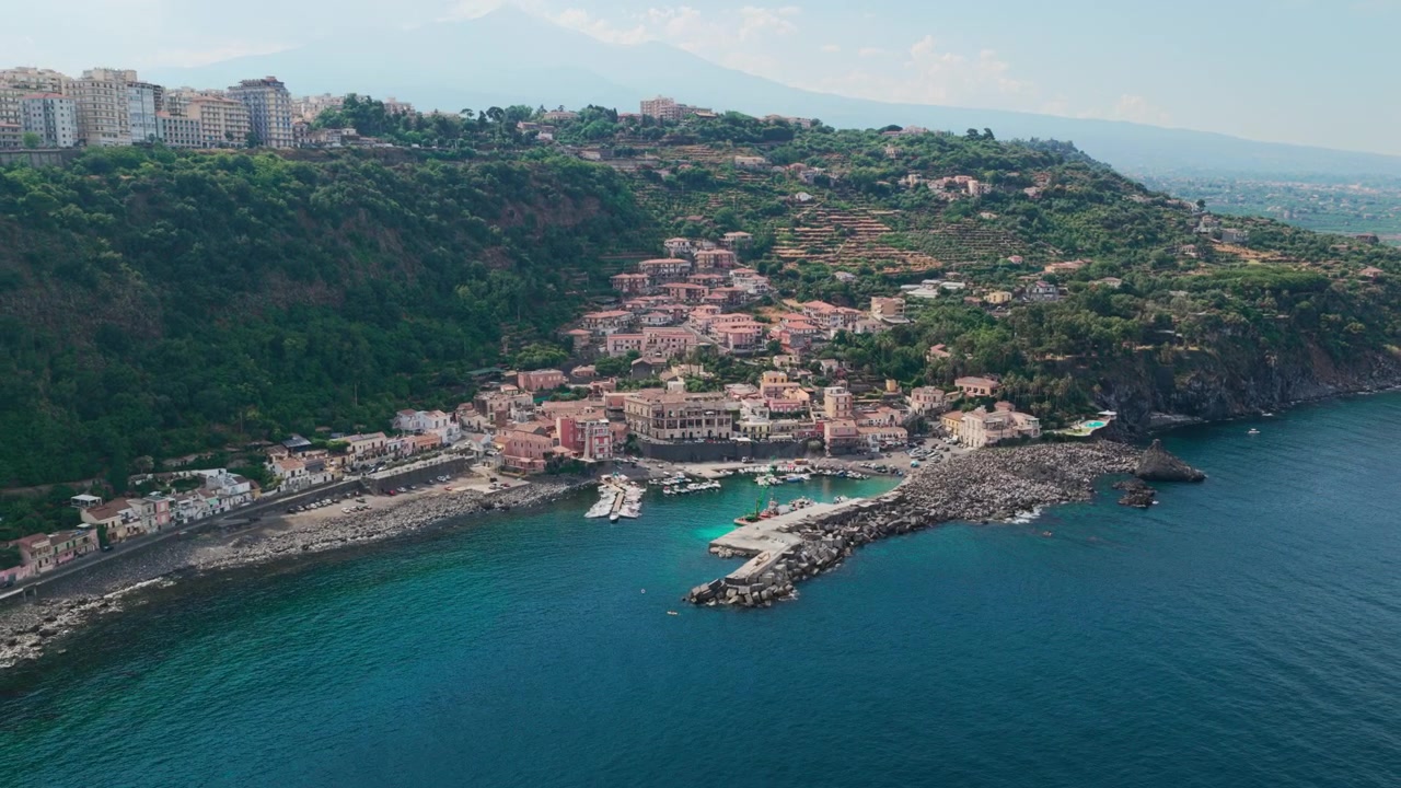 Ampia veduta aerea di Santa Maria la Scala, un villaggio di pescatori con acqua cristallina e scogliere di lava basaltica vicino all'Etna ad Acireale, Catania, Sicilia, Italia, una destinazione popolare sulla costa ionica.