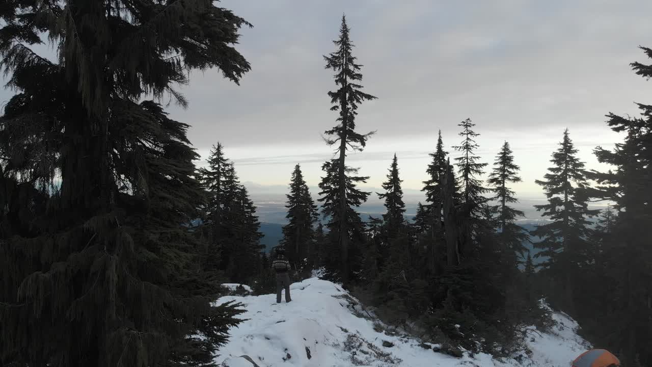 toma aérea de una persona en la cima de la montaña grouse contemplando la vista de vancouver columbia británica al atardecer
