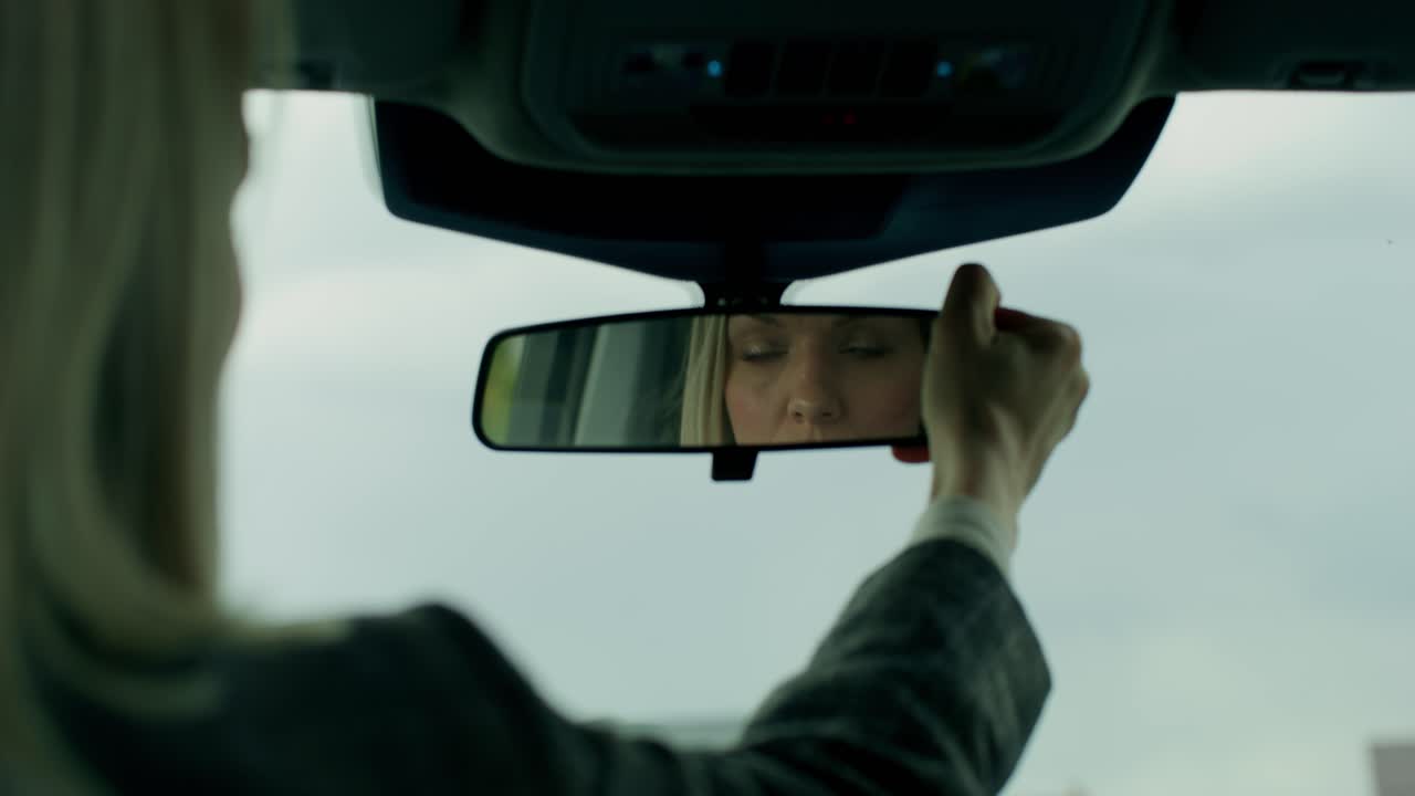 자동차 의 후방 거울 을 조정 하는 여자