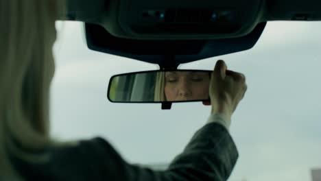 mujer ajustando el espejo retrovisor en el coche