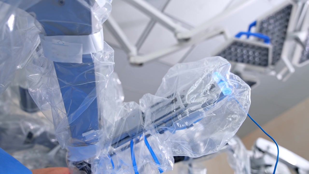 Bracci manipolatori del chirurgo robotico rivestiti in plastica per la sterilità. Le parti operative del sistema chirurgico Da Vinci si muovono durante l'intervento. Vista dal basso.