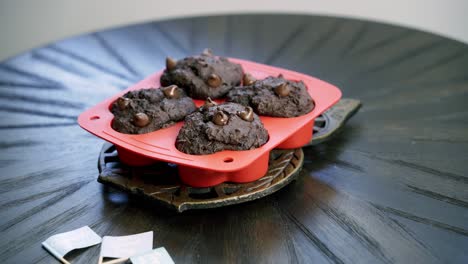 tomando muffins de chocolate en forma de remolacha en forma de corazón fuera del horno y colocándolos en la mesa para enfriar el día de san valentín