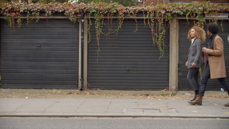 stylish young couple walking past garages on city street