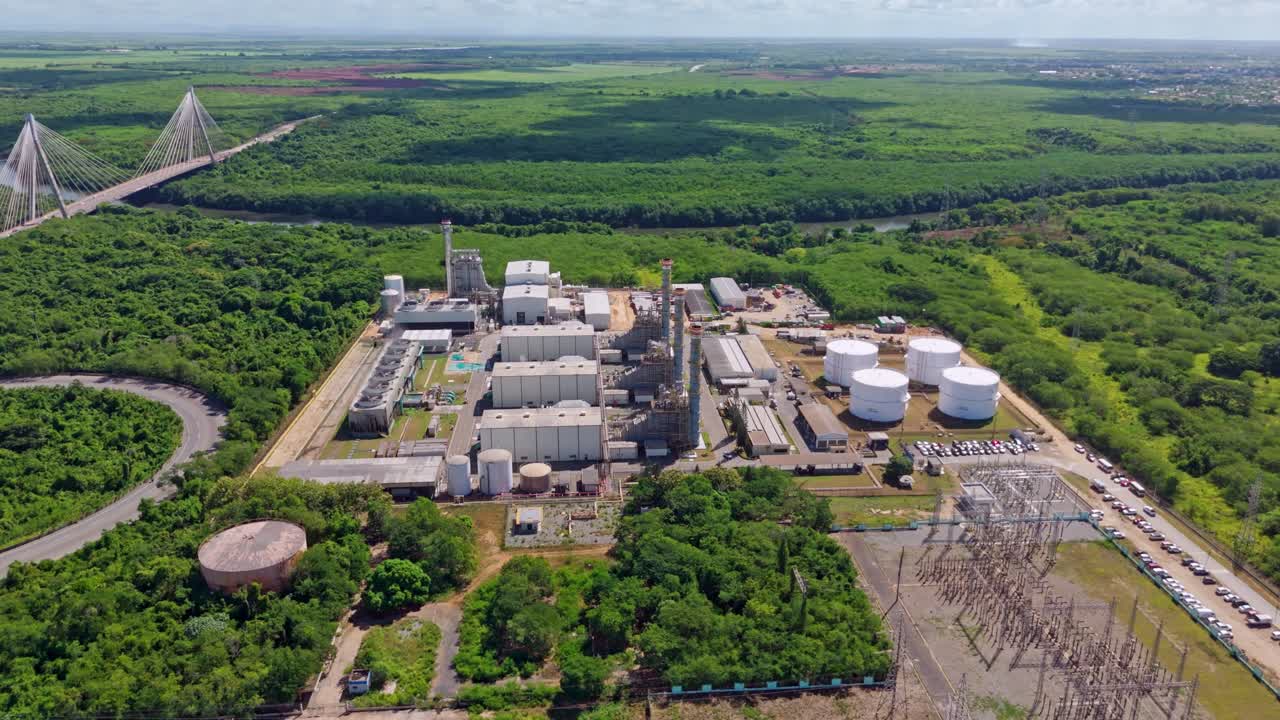 Aerial drone view of Energa 4 power plant, storage tanks, and Mauricio Baez Bridge in background, San Pedro de Macoris, Dominican Republic