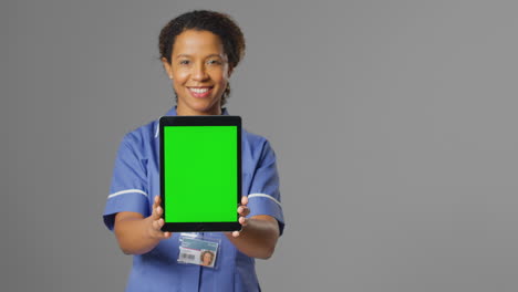 Portrait-Of-Smiling-Nurse-Wearing-Uniform-Holding-Digital-Tablet-With-Blank-Green-Screen