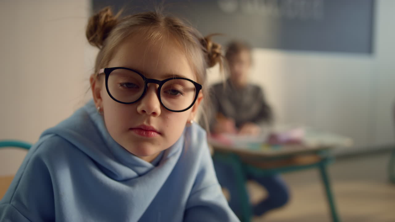 Ritratto di ragazza seria a scuola. Bella studentessa con gli occhiali che guarda l'obiettivo.