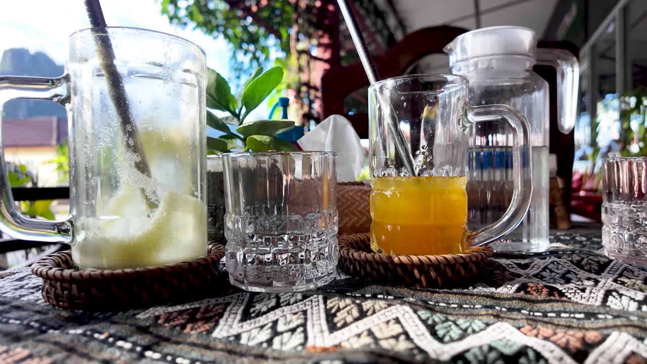 Multiple empty drink glasses sitting on a wicker tray on an outdoor cafe table in Vang Vieng. push forward shot