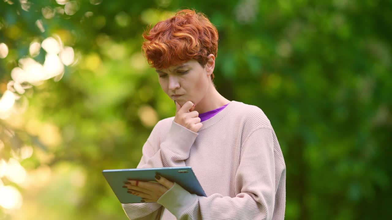 Woman using tablet outdoors, thinking and reacting