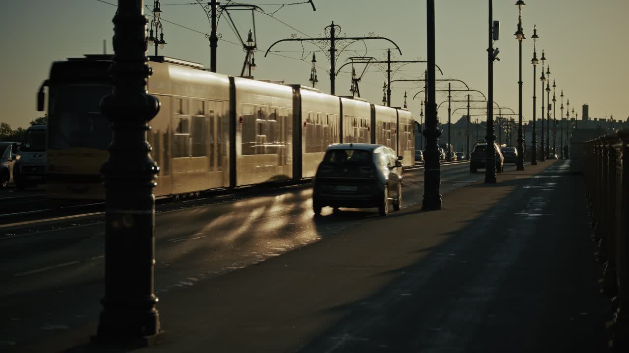 Cars drive along streetlamp lined bridge under hazy sky during late afternoon, Budapest Hungary