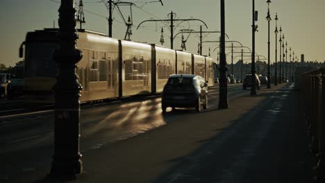 cars drive along streetlamp lined bridge under hazy sky during late afternoon, budapest hungary