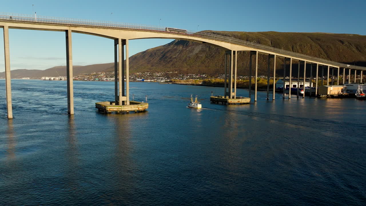 Tromsø Bridge with boat passing underneath, Tromsø, Norway. Aerial drone lateral view