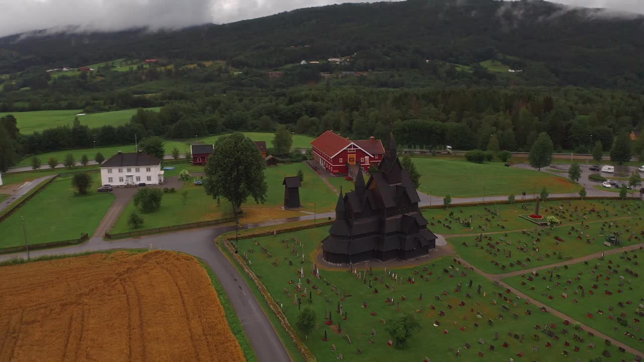 The famous wooden church in norway, surrounded by green fields and hills, aerial view