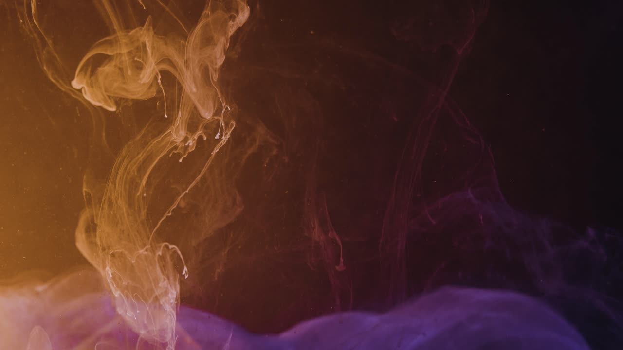 cámara lenta de gotas de tinta de pintura colorida que caen en el agua contra la pantalla negra