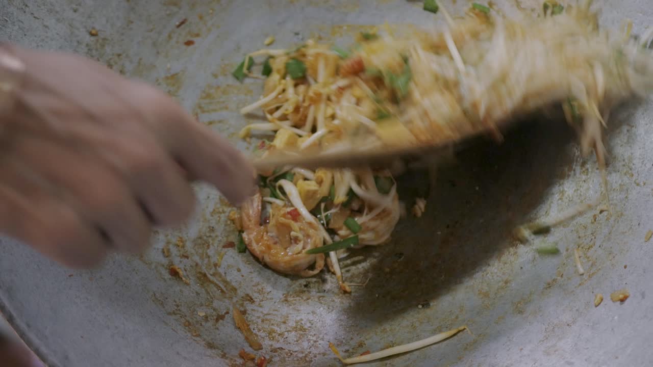 Hvite asiatiske nudler og tofu som kokes og wokkes i pannen, for å tilberede Pad Thai