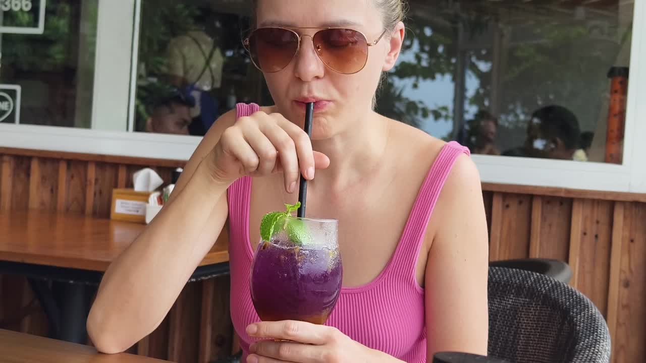 mujer disfrutando de una refrescante bebida púrpura al aire libre
