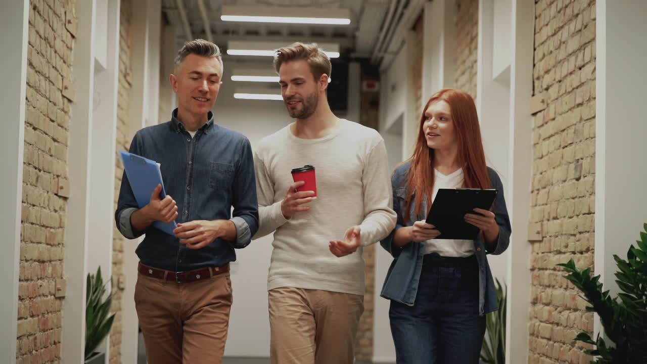 Business men and woman walking towards the camera in a corridor. People go to a work meeting.