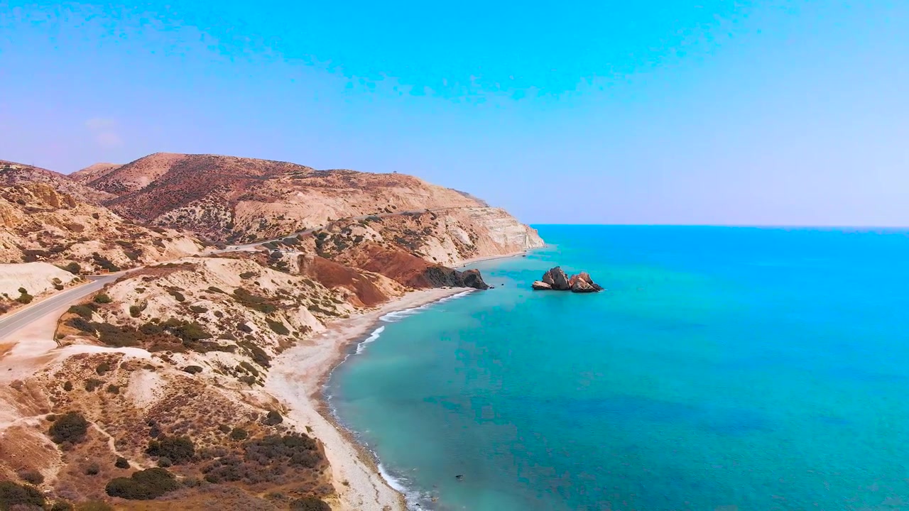 Slow aerial view flying along the coast of pafos away from Aphrodite's Rock on the coast of Paphos Cyprus