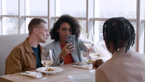 friends enjoying a meal and looking at a phone in a restaurant.