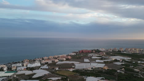 Aerial-view-panning-from-sea-to-mountains-at-sunset