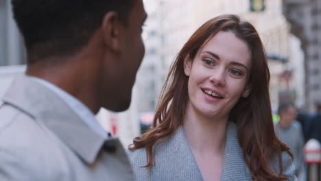 two millennial business colleagues standing on a street in london having a conversation, selective focus, close up