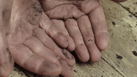 un par de manos sucias abiertas sobre fondo de madera