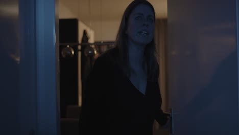 mujer preocupada abriendo la puerta del pasillo por la noche y gritar