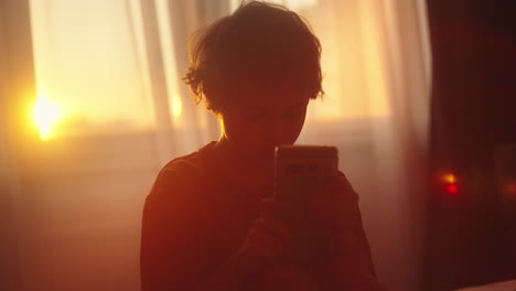 Child using a smartphone at sunset