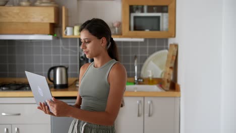 mujer joven trabajando en una computadora portátil en la cocina